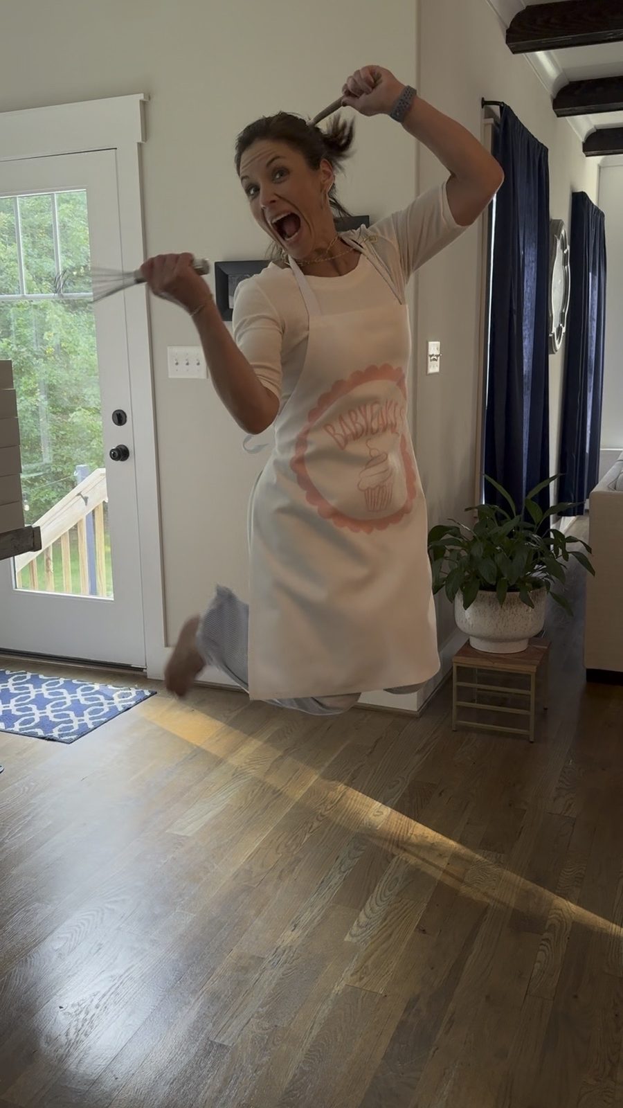 Jen mid-jump in a Babycakes apron, whisk in hand